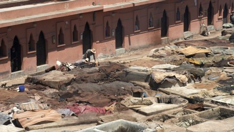MARRAKESH, MOROCCO- JUNE, 11, 2019: close high angle view of workers at an ancient tannery in marrakesh, 