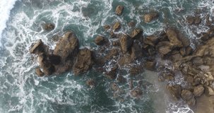 Rocks of Bali coastline. Balinese southern coast cliffs being washed by clear azure ocean. Waves crashing on rocks. Aerial video shooting from a drone. 4k footage
