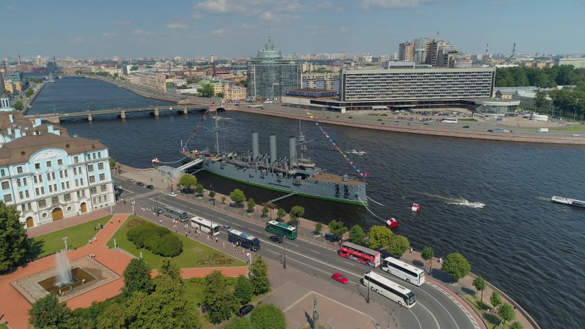 From great height St. Petersburg historical cityscape. Big navy ship cruiser Aurora museum. Petrovskaya embankment. Neva river boats sail. Road traffic. People walk. Epic overall plan. Aerial 4k