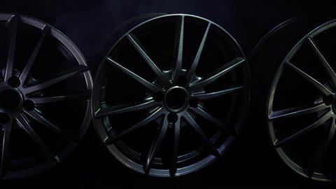 Beautiful designer car alloy wheels on a black background with smoke, copy space, luxury