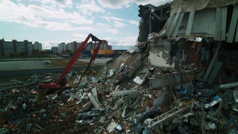 OMSK/RUSSIA - MARCH 02 2020: Large demolition site of old dangerous hockey arena with modern excavators disassembling debris aerial motion on March 02 in Omsk