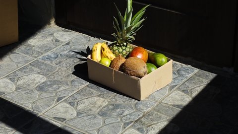Courier man leaving grocery bag with exotic fruits in front door