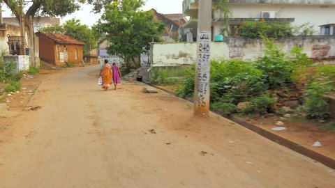 Yeleswaram , Andhra Pradesh / India - 11 02 2019: Indian village woman walking hand in hand with young girl Tracking shot along Indian village street in late afternoon light. Yeleswaram. Eleswaram , A
