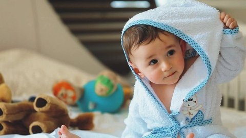 Close up shot of a cute newborn baby in a white bathrobe, after bathing and smiling in the camera. Concept of children,baby, parenthood, childhood, life