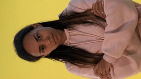 Multiethnic young woman dissatisfied with something. There is yellow background. Video with Vertical Screen Orientation 9:16