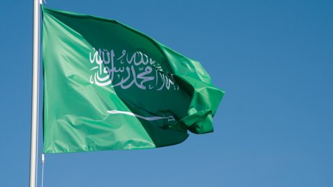 State Flag of Saudi Arabia. The Big State Flag is illuminated by the sun and flutters epically in the wind against the blue sky. Slow Motion 120 fps