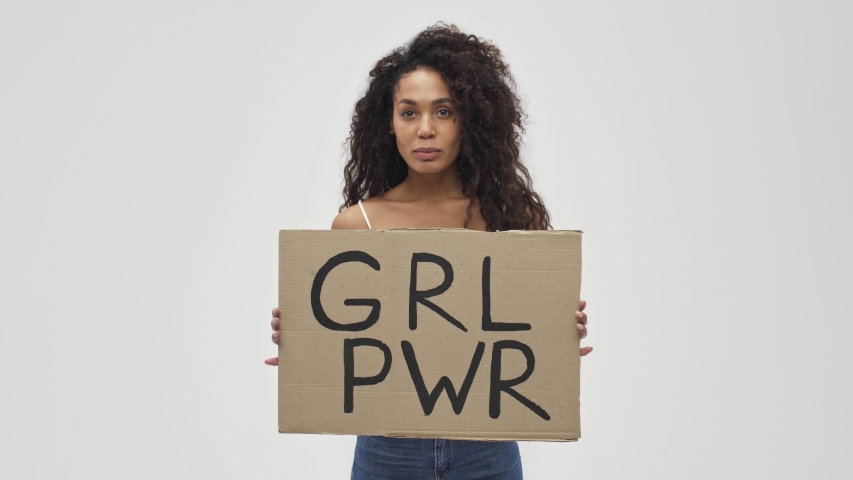 Young african serious pretty amazing woman posing isolated over white wall background holding blank with feminist text