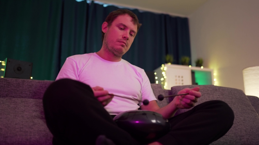 a man sits at home and plays around on the hapi drum warm atmosphere on isolation