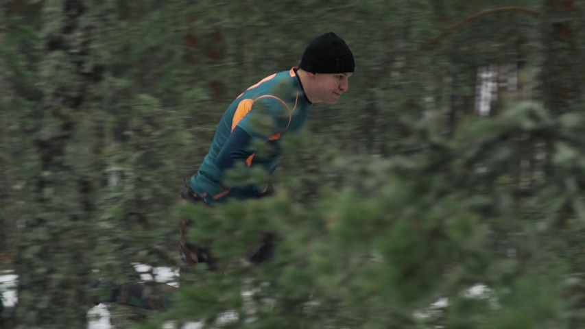 a man runs through the winter forest snow around, flashed tree trunks