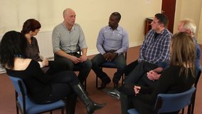 Support group therapy - People sat in circle for a recovery meeting - One man speaks while the others listen. Close Up - Stock Video Clip Footage - Tracking Shot