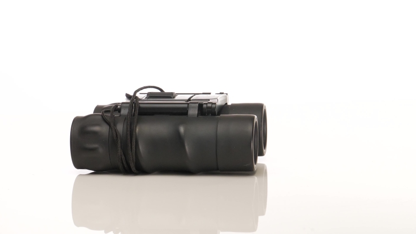 A pair of black binoculars rotating in circular motion on a white background