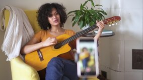 black girl recording guitar song cover on phone singing Spbd. song instrumental performance. blogger filming tutorial for amateur singers on youtube. video for social media
