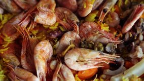 Cooking sea food paella on paellera pan in the kitchen.Delicious Spanish cuisine in close up footage.Seafood,curcume spice,wild rice and tomatoes being fried in restaurant for lunch