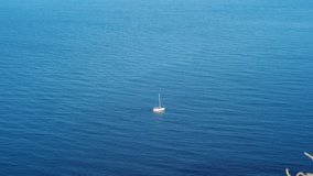 aerial view of white yacht sailing on open blue sea at sunny summer morning