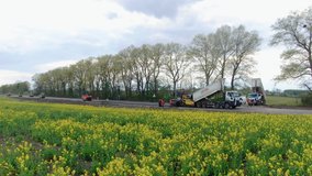4K video. Side view of road works with asphalt paver (asphalt laying machine or asphalt spreading machine) and road workers on the motorway