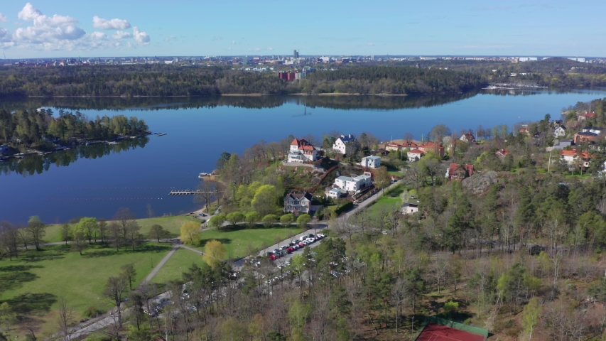 Drone shot of Stockholm city suburb Djursholm in Danderyd. Downtown city center in distant background at horizon. Richest community in Sweden in archipelago inlet Royalty-Free Stock Footage #1052302372