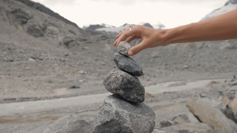 Detail of person stacking rocks by the river near glacier, shot in Graubünden Canton, Switzerland. People life balance concept