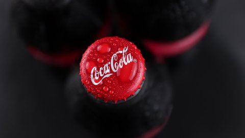 Minsk, Belarus, 05.2020 three wet bottles with red coca-cola classic logo rotating and stopping against the black background top view. carbonated drinks are fogged up and water droplets running down