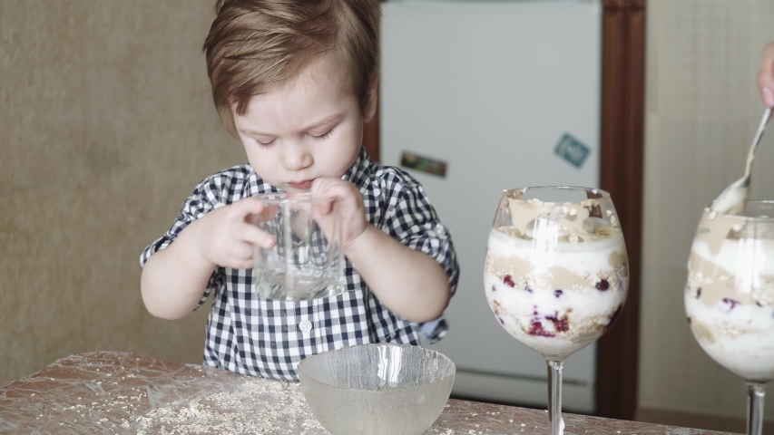 Boy child helps mom in the preparation of a milkshake with oatmeal and bananas with berries