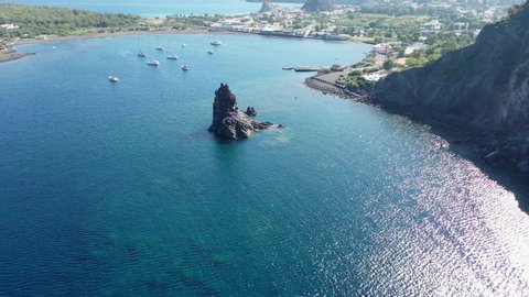 Beautiful panoramic aerial video from flying drone of the black sand beach with yachts in small haven in Porto di Ponente, in Vulcano, Lipari and Salina Aeolian Islands Tyrrhenian Sea, Sicily, Italy