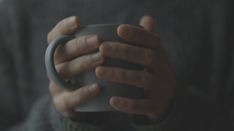 A men's hands are holding a cup of aromatic coffee. A man warms his hands with a cup of coffee. A cup in men's hands.