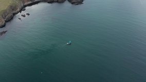 Aerial fly over a boat in clear green seawater around picturesque rocks, Black sea coast, Bulgaria