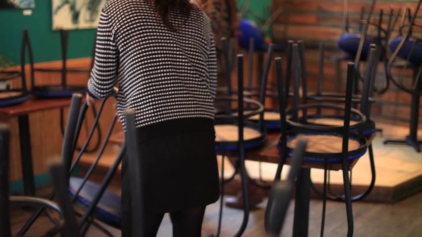 Selective focus of two young female waitress workers aligning and preparing table and chairs in a restaurant during opening hours for customers Royalty-Free Stock Footage #1052314207