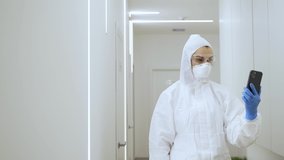 A female doctor in a protective suit will talk by video link and shows the gesture ok
