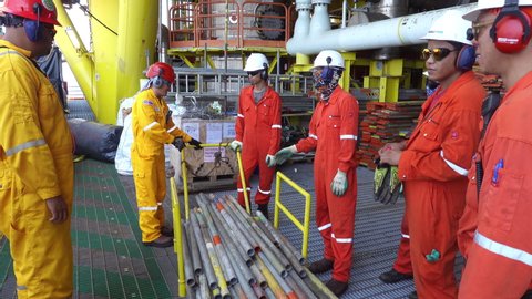 KELANTAN, MALAYSIA - AUG 19 2019 : Unidentified Safety Officer with yellow coverall and red hard hat having discussion with workers about ergonomic hazard in work place.