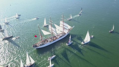 Lisbon / Portugal - 02 23 2020: Aerial, high angle, drone shot around the NRP Sagres III barque, leading a convoy of sailboats, on the Atlantic ocean, bright, sunny day, in Lisbon, Portugal