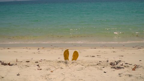 Flip flops on Whitsundays beach, on white sand. Thongs in sandcastle with aqua turquoise ocean background. Travel, holiday, vacation, paradise, exotic. Whitsundays Islands, Queenstown, Australia. HD.