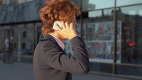 Businessman or office worker is actively talking on the mobile phone on the street. Man with glasses in a suit talking on the phone.