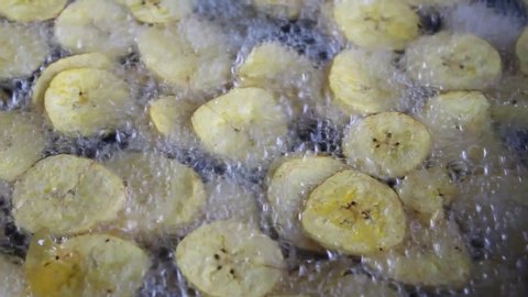 close up frying plantains in boiling oil. Delicious tropical Amazonian snack cooked in a traditional way. healthy food vegetarian and natural. Deep fried banana chips in slices