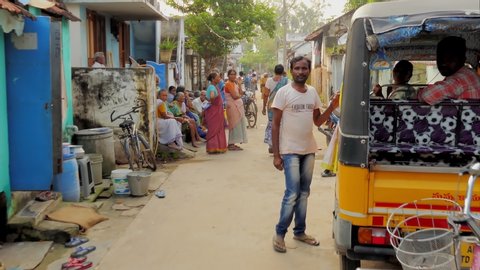 Yeleswaram , Andhra Pradesh / India - 11 02 2019: Forward tracking shot along Indian village street past an auto rickshaw and village women congregating in front of their houses in the late afternoon.