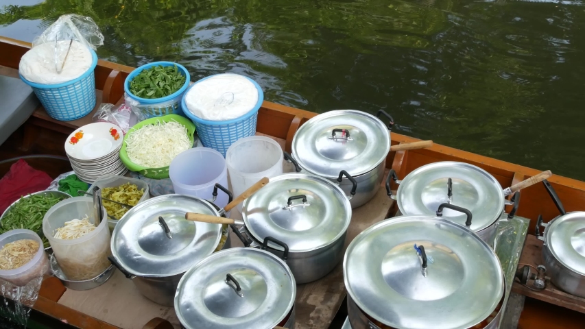 Iconic asian Lat Mayom floating market. Khlong river canal, long-tail boat with tropical exotic colorful fruits, organic locally grown vegetables. Top view of harvest and street food in wooden canoe.