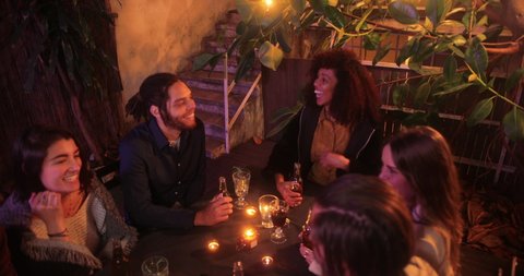 Multi-ethnic friends couples laughing talking over drinks on patio Video stock