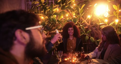 Close up multi-ethnic friends and couples toasting beer on patio