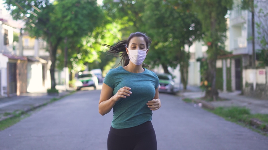 Portrait of young and fit woman running and jogging alone on the empty street in city center wearing protective face mask
 Royalty-Free Stock Footage #1052358553