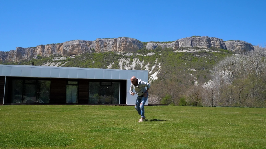 Quarantine. At home in the mountains. Villa. A Middle-aged man somersaulting on the grass