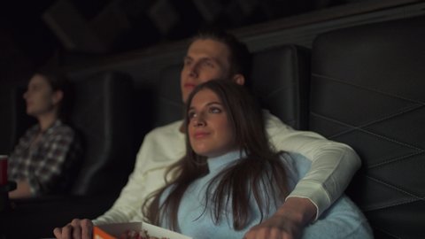 Portrait of a Young couple in a movie theater, watching a movie on a big screen, a date, the effect of glowing light.