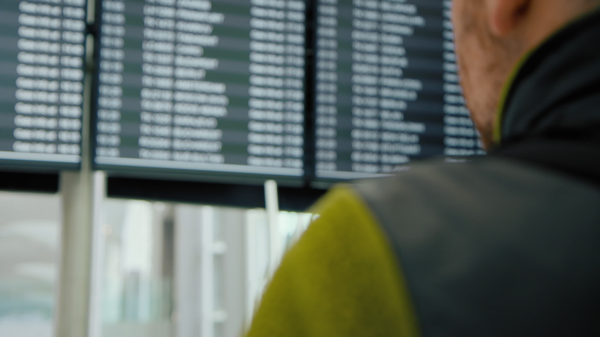 Citizen try to return home. Traveller or tourist search for cancelled or delayed flight on information screen in airport. Vacation or summer holiday cancellation. Suspended flights to spain, barcelona Royalty-Free Stock Footage #1052362810