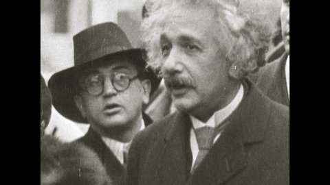 1960s: Albert Einstein standing with crowd. Press with cameras. Press around Einstein, man shakes Einstein's hand. Close up of Einstein.