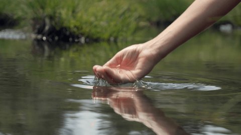 Human hand cupped to catch the fresh water from the lake, pure clean nature. Body care healthy natural. Slow motion  