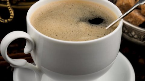 Coffee is mixed in a cup with a spoon