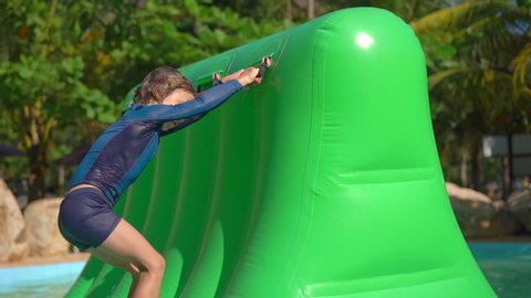 Little boy on an inflatable obstacle course in an aqua park. Summer concept. Slowmotion shot
