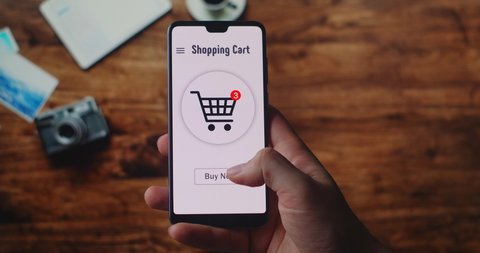 BUY NOW button being pressed on a smartphone screen. Woman at Home on Couch in Living Room Using Smartphone Buys in Internet Shop. Woman Orders Food Home In An Online Store Using a Smartphone.