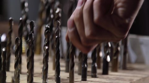 Close-up of a worker's hand choosing drills for work. The concept of production and construction