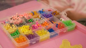 Hands of little baby girls, sisters, and their mother learning to play with colorful beads at home - Beading with Your Children