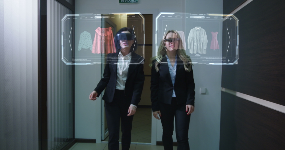 Medium long shot of two women walking through corridor while using holographic vr technology for online shopping Royalty-Free Stock Footage #1052399023