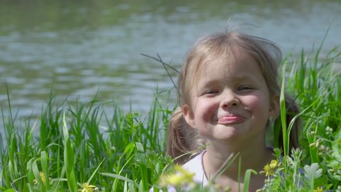 Portrait of a smiling little girl. Funny baby in tall grass. Tiny kid have fun, enjoy nature outdoors. 4K